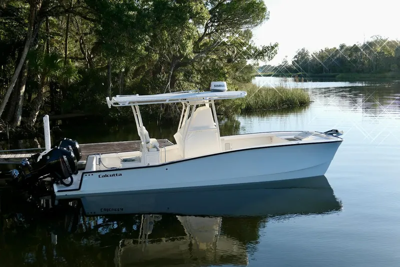 Yacht Photos Pics 2020 Calcutta 263 Center Console boat docked on a serene lake.
