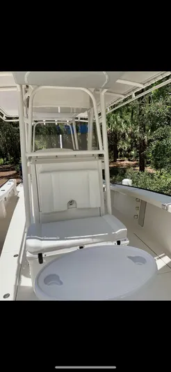 Yacht Photos Pics 2020 Calcutta 263 Center Console boat interior with seating and console, surrounded by lush greenery.