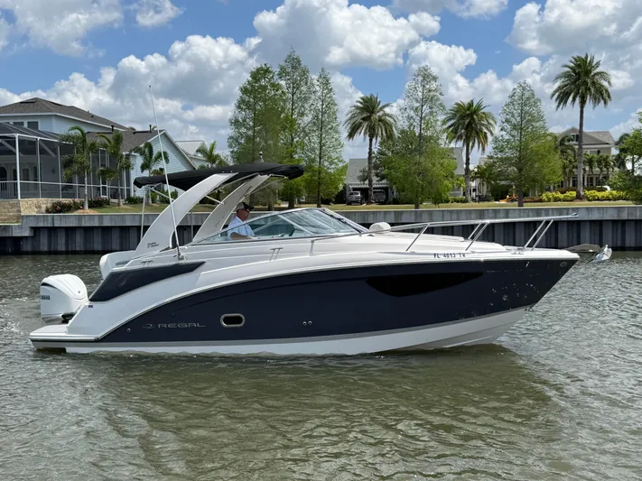  Yacht Photos Pics 2024 Regal 26 XO boat cruising on a sunny day with palm trees in the background.