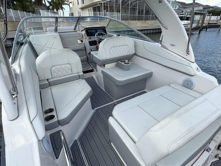  Yacht Photos Pics 2024 Regal 26 XO boat interior with white seating and modern dashboard, docked by waterfront homes.