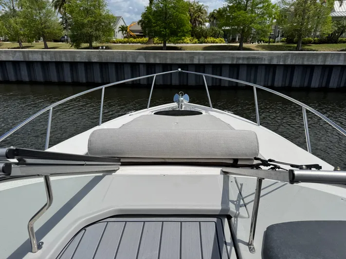  Yacht Photos Pics 2024 Regal 26 XO boat bow view with railing and seating, docked by a canal.