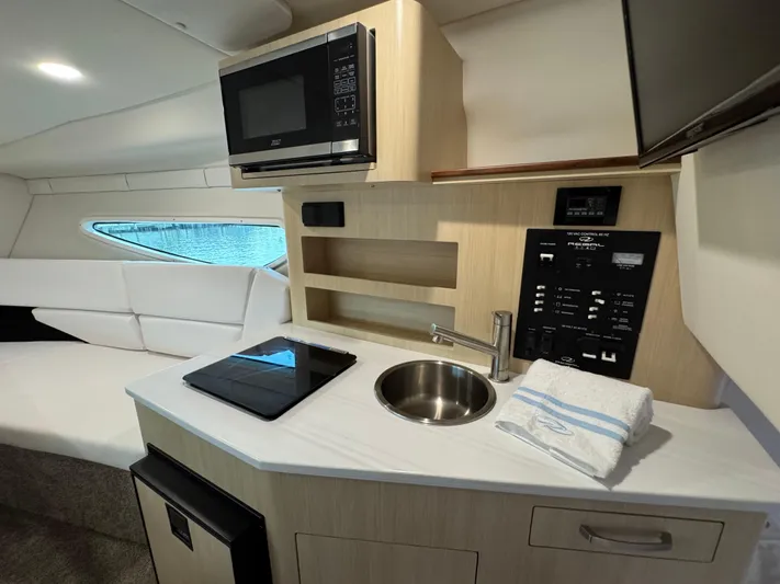  Yacht Photos Pics 2024 Regal 26 XO boat interior with kitchenette, microwave, sink, and seating area.