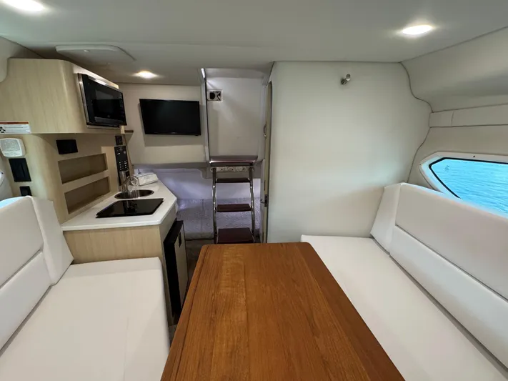  Yacht Photos Pics 2024 Regal 26 XO cabin interior with kitchenette, seating, and wooden table.