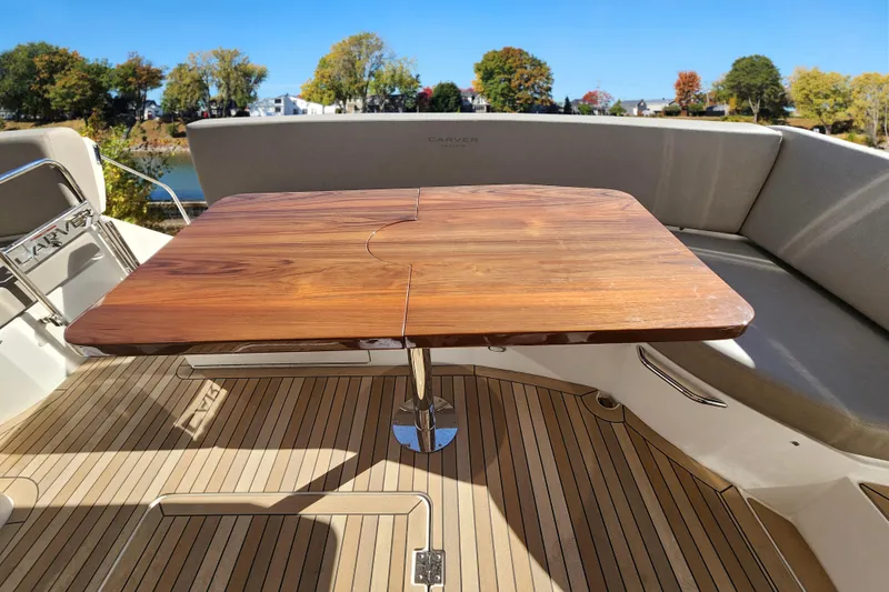  Yacht Photos Pics 2021 Carver 52 Command Bridge with wooden table and cushioned seating on deck.