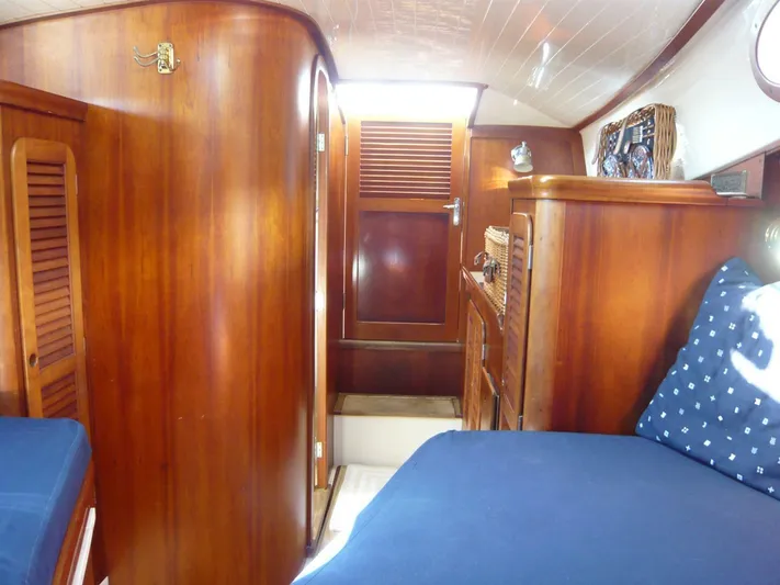 Courage Yacht Photos Pics Interior of 1998 Hinckley 36 Classic yacht with wooden cabinetry and blue bedding.