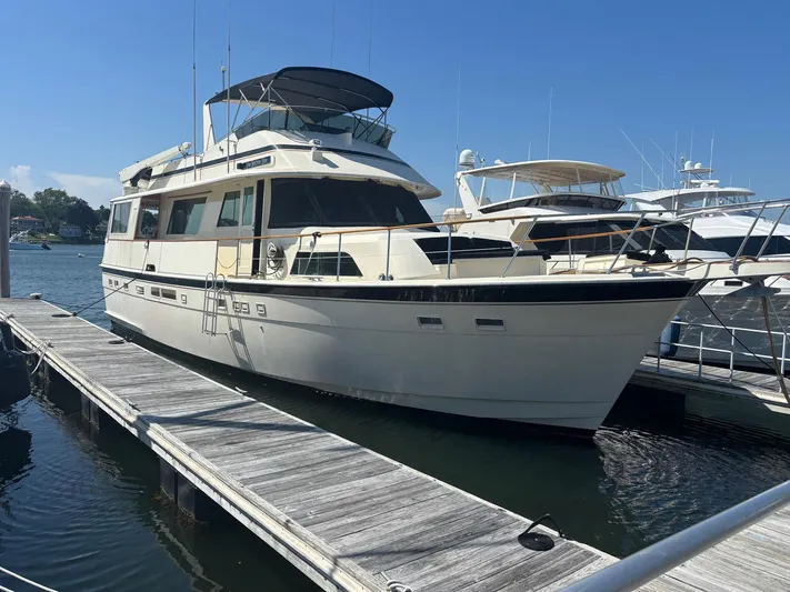 The Bottom Line Yacht Photos Pics 1987 Hatteras Flybridge yacht docked at marina under clear blue sky.