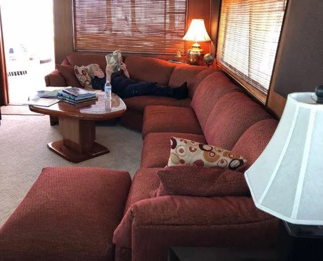 The Bottom Line Yacht Photos Pics Cozy 1987 Hatteras Flybridge interior with red sectional sofa and warm lighting.