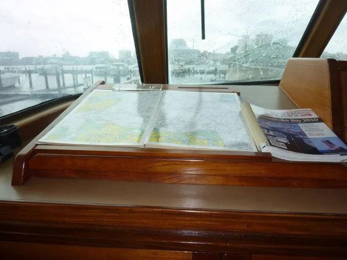 The Bottom Line Yacht Photos Pics Navigation station on 1987 Hatteras Flybridge with maps and guidebook.