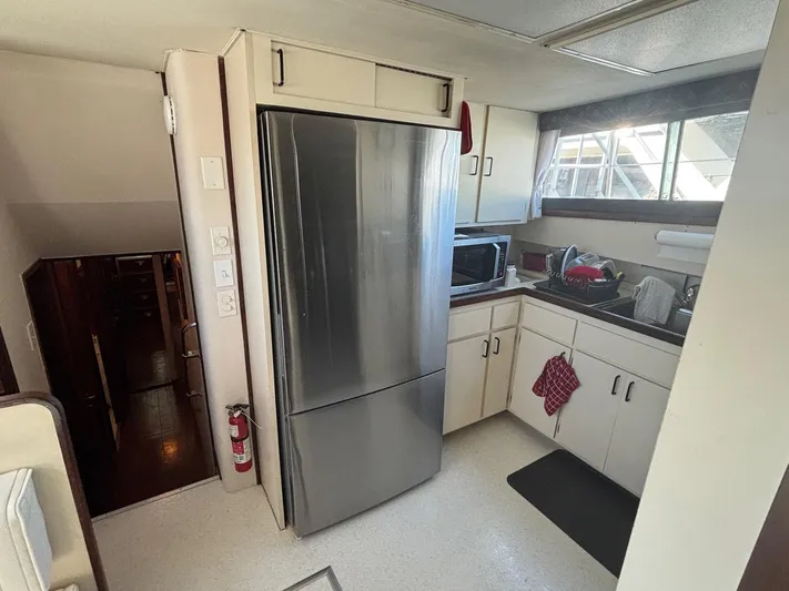 The Bottom Line Yacht Photos Pics 1987 Hatteras Flybridge kitchen with stainless steel fridge, microwave, and sink area.