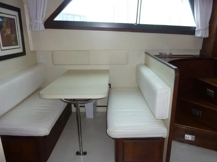 The Bottom Line Yacht Photos Pics 1987 Hatteras Flybridge interior with white upholstered seating and dining table.