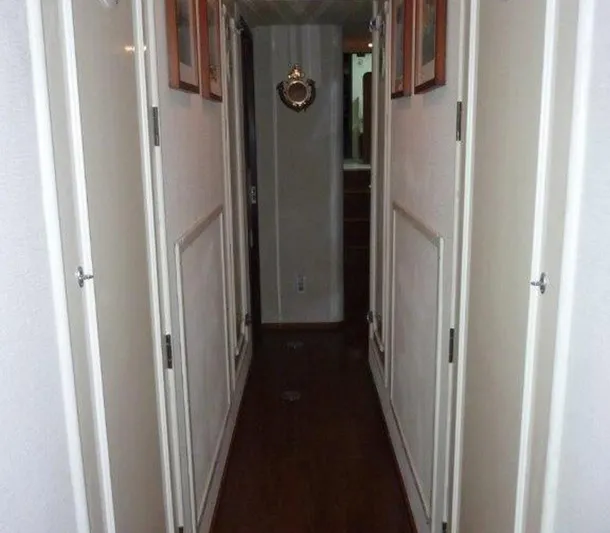 The Bottom Line Yacht Photos Pics Narrow hallway inside a 1987 Hatteras Flybridge yacht, featuring wooden flooring and white doors.