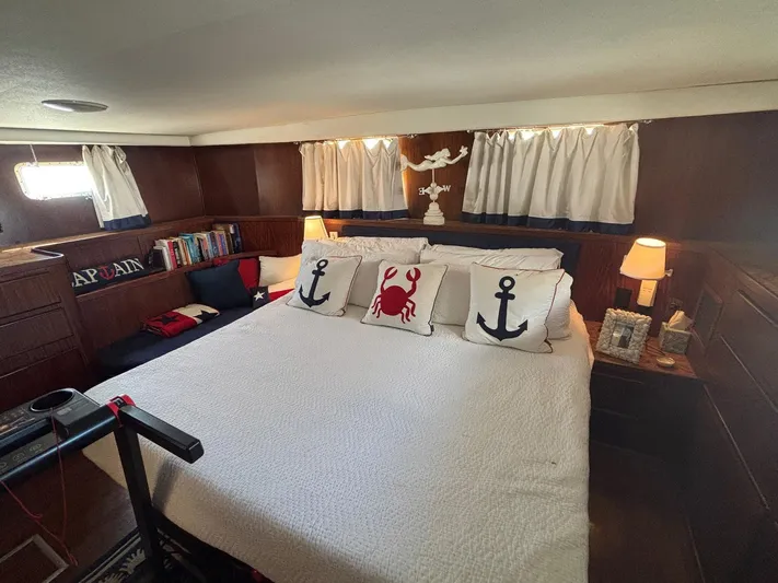 The Bottom Line Yacht Photos Pics Cozy bedroom in 1987 Hatteras Flybridge yacht with nautical-themed decor and plush bedding.