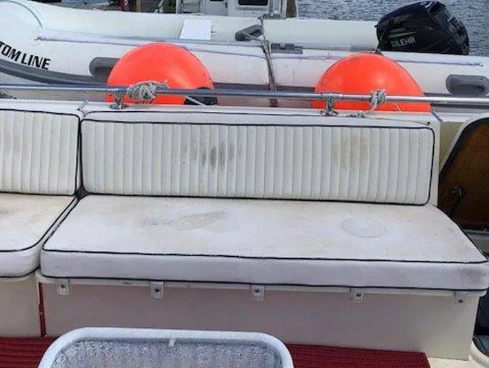 The Bottom Line Yacht Photos Pics 1987 Hatteras Flybridge boat seating area with white cushions and orange buoys in the background.
