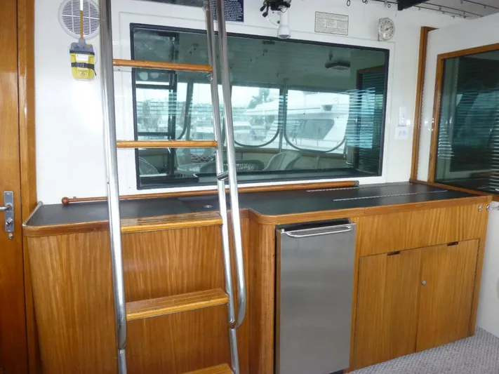 The Bottom Line Yacht Photos Pics 1987 Hatteras Flybridge interior with wooden cabinetry, ladder, and window view.