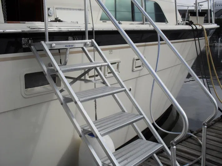The Bottom Line Yacht Photos Pics 1987 Hatteras Flybridge yacht with metal boarding stairs at dockside.
