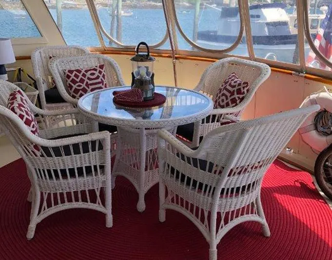 The Bottom Line Yacht Photos Pics 1987 Hatteras Flybridge interior with wicker furniture and red accents, overlooking marina.