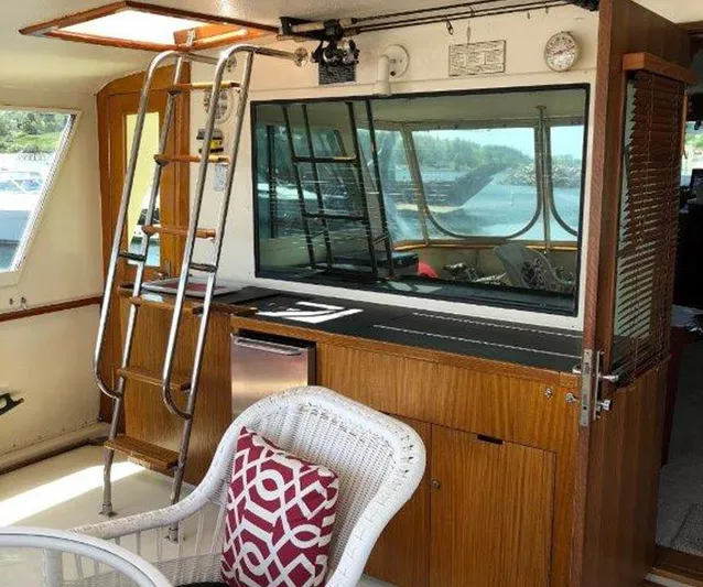 The Bottom Line Yacht Photos Pics 1987 Hatteras Flybridge interior with ladder, wicker chair, and window view.