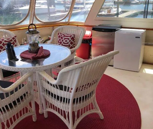 The Bottom Line Yacht Photos Pics 1987 Hatteras Flybridge interior with wicker chairs, round table, and marina view.