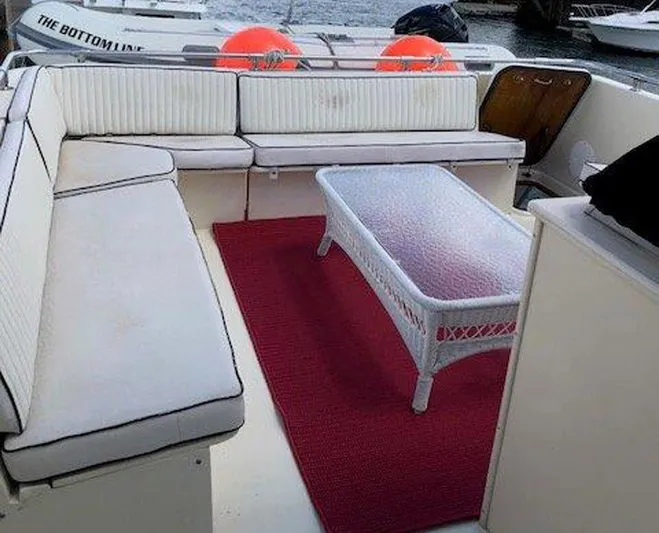 The Bottom Line Yacht Photos Pics 1987 Hatteras Flybridge yacht interior with white seating, glass table, and red rug.