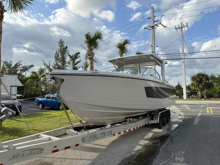  Yacht Photos Pics 2020 Aviara AV32 OB boat on trailer, parked roadside under cloudy sky.