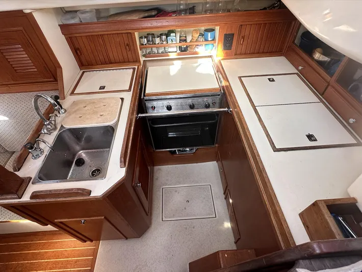 Next Course Yacht Photos Pics 2001 Island Packet 320 yacht kitchen with stove, sink, and wooden cabinetry.