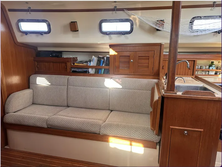 Next Course Yacht Photos Pics Interior of 2001 Island Packet 320 sailboat with cushioned seating and wooden cabinetry.