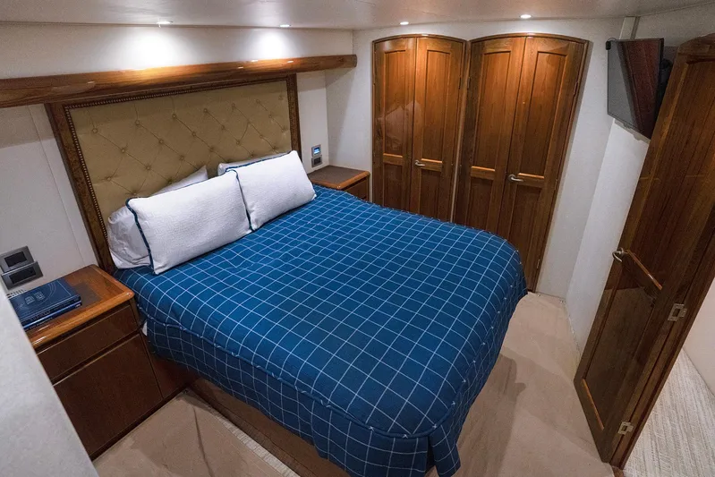 Serenity Now Yacht Photos Pics Luxurious bedroom in 2014 Viking 66 yacht with blue checkered bedding and wooden cabinetry.