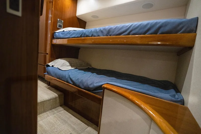Serenity Now Yacht Photos Pics Interior of 2014 Viking 66 yacht featuring cozy wooden bunk beds with blue bedding.