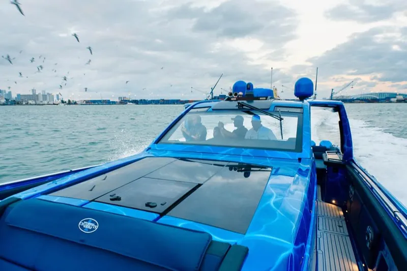  Yacht Photos Pics 2024 Cigarette 59 Tirranna speedboat cruising on open water with city skyline backdrop.