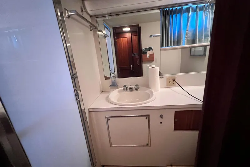 Grand Adventure Yacht Photos Pics 1972 Hatteras 58 Yacht Fisherman bathroom with sink, mirror, and wooden accents.