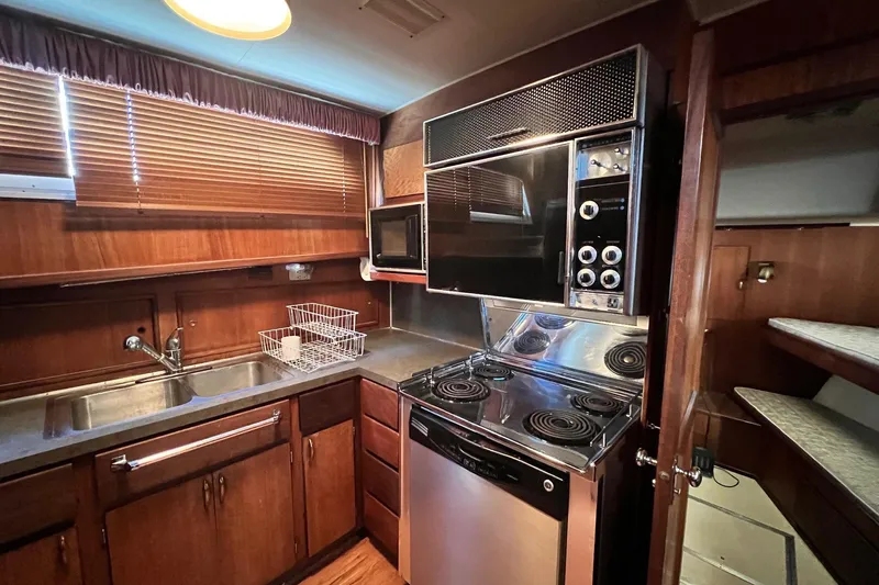 Grand Adventure Yacht Photos Pics 1972 Hatteras 58 Yacht Fisherman kitchen with stove, microwave, and wooden cabinetry.