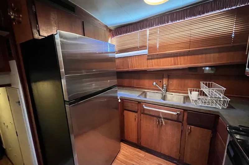 Grand Adventure Yacht Photos Pics 1972 Hatteras 58 Yacht Fisherman kitchen with stainless steel fridge and wooden cabinets.