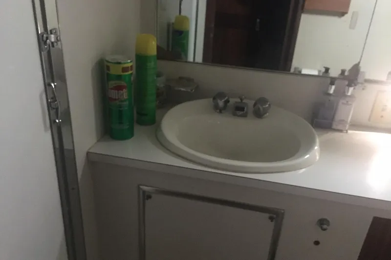 Grand Adventure Yacht Photos Pics Bathroom sink area on 1972 Hatteras 58 Yachtfish, featuring cleaning supplies and mirror.