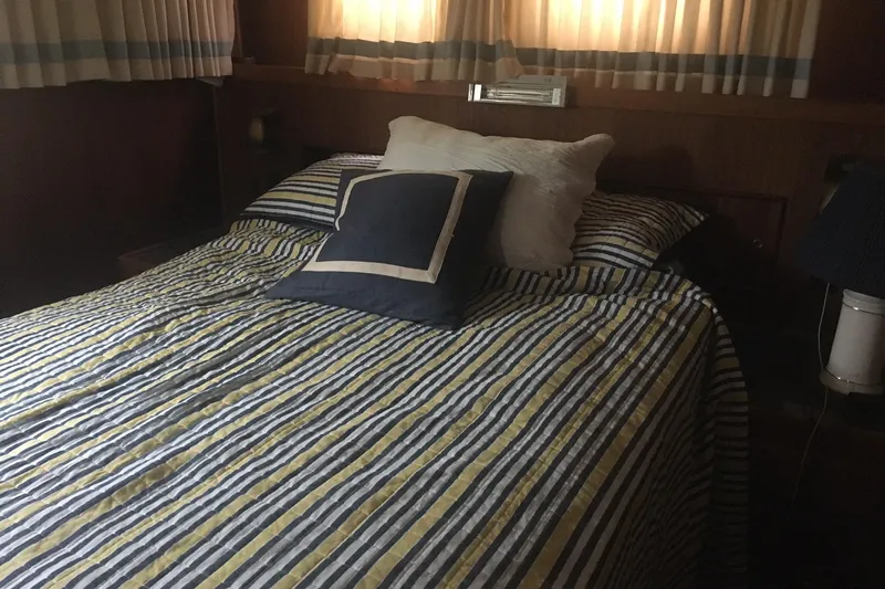 Grand Adventure Yacht Photos Pics Cozy bedroom interior on 1972 Hatteras 58 Yachtfish with striped bedding and soft lighting.