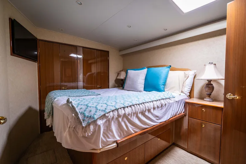  Yacht Photos Pics Luxurious bedroom interior of a 2005 Viking 56 yacht with cozy bedding and elegant wood finishes.