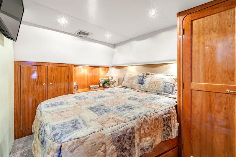 Sadie Ann II Yacht Photos Pics Luxurious bedroom interior of 2005 Ocean Yachts 50 Super Sport with wood cabinetry and cozy bedding.