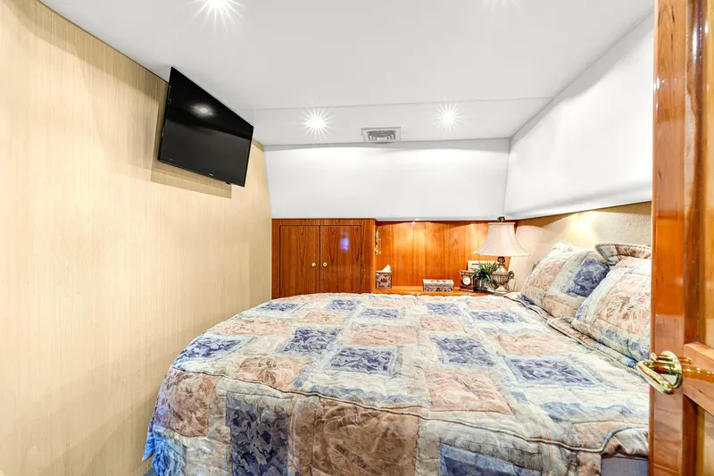 Sadie Ann II Yacht Photos Pics Luxurious bedroom in 2005 Ocean Yachts 50 Super Sport with cozy bedding and wall-mounted TV.