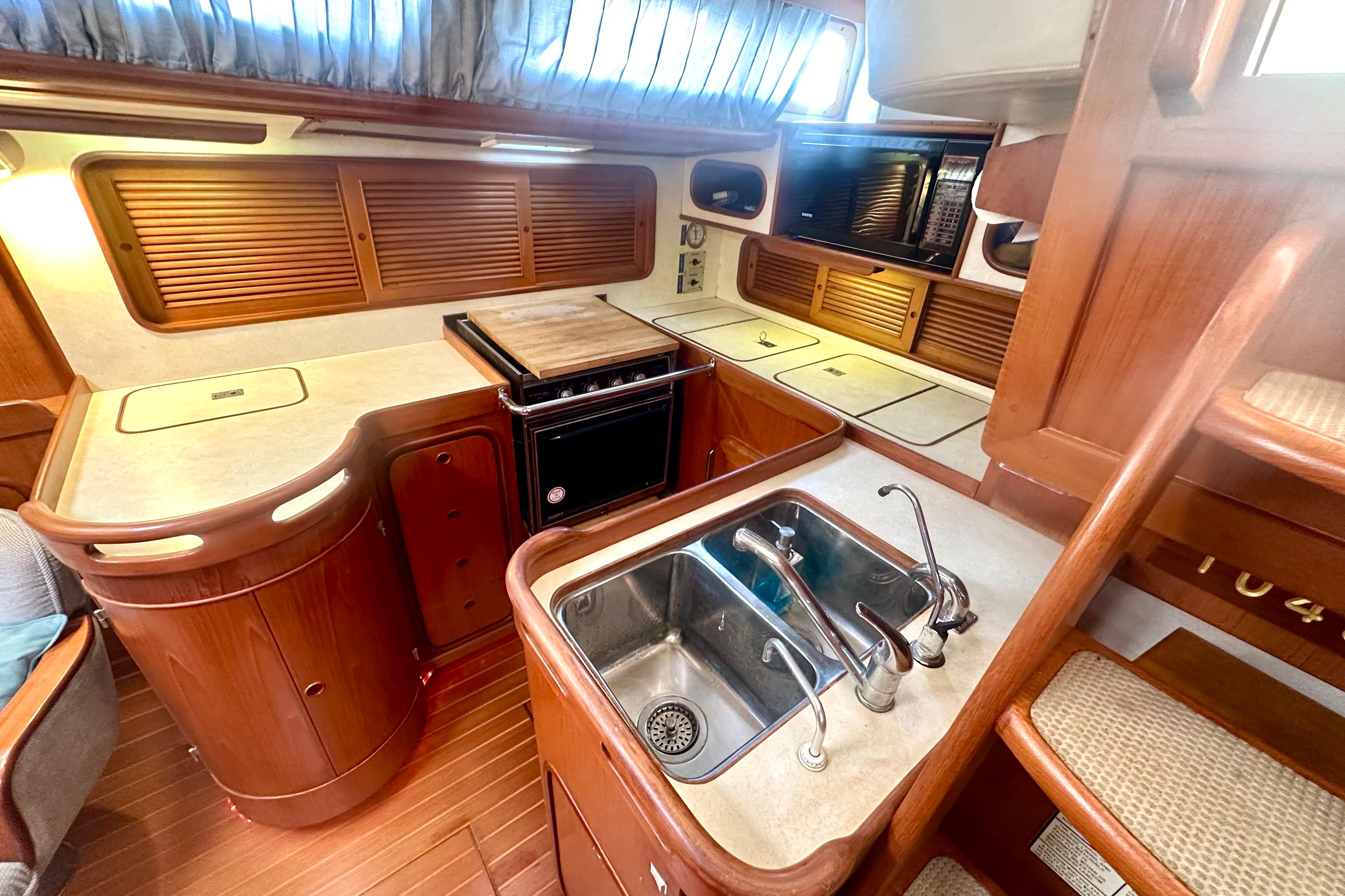 Interior of 1991 Taswell Sloop featuring a well-equipped kitchen with wooden cabinetry.