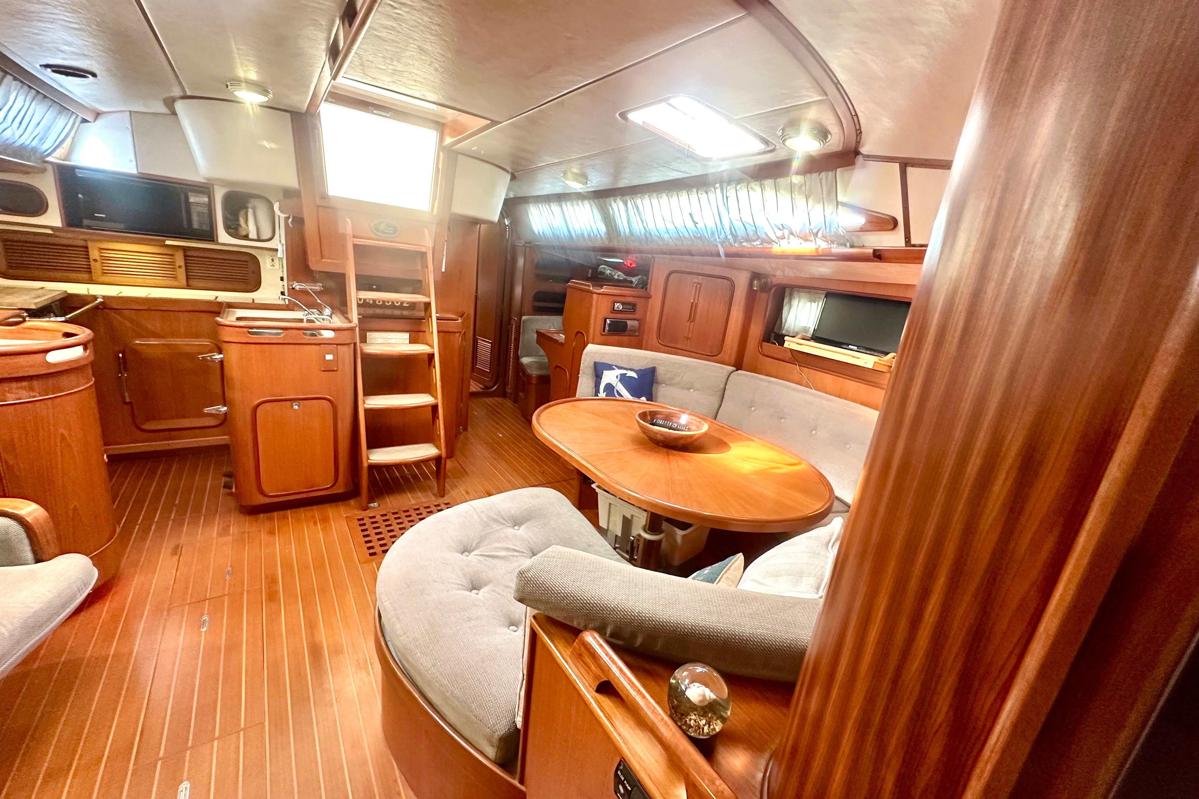 Luxurious 1991 Taswell Sloop interior with wooden finishes and cozy seating area.