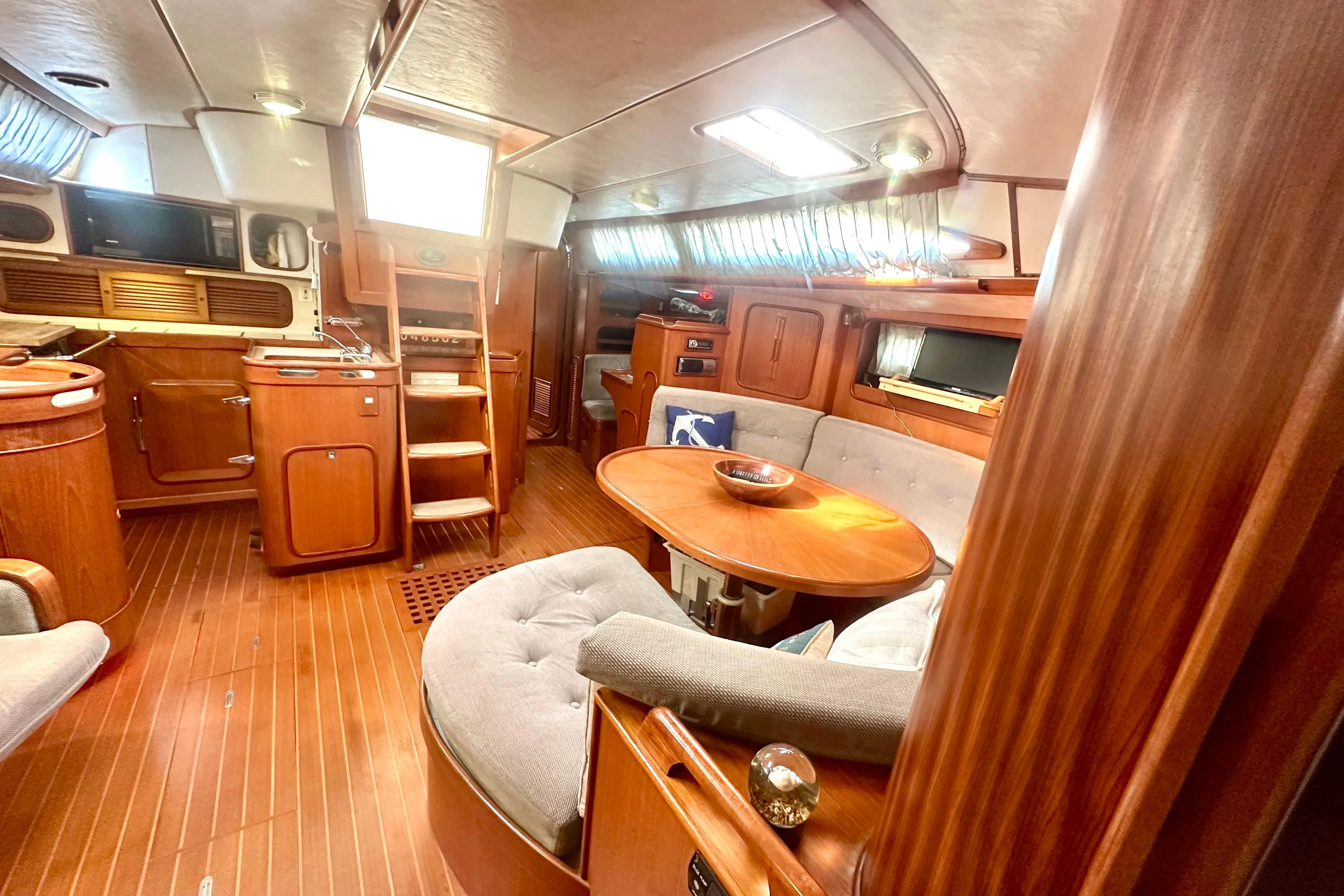 Luxurious 1991 Taswell Sloop interior with wooden finishes and cozy seating area.