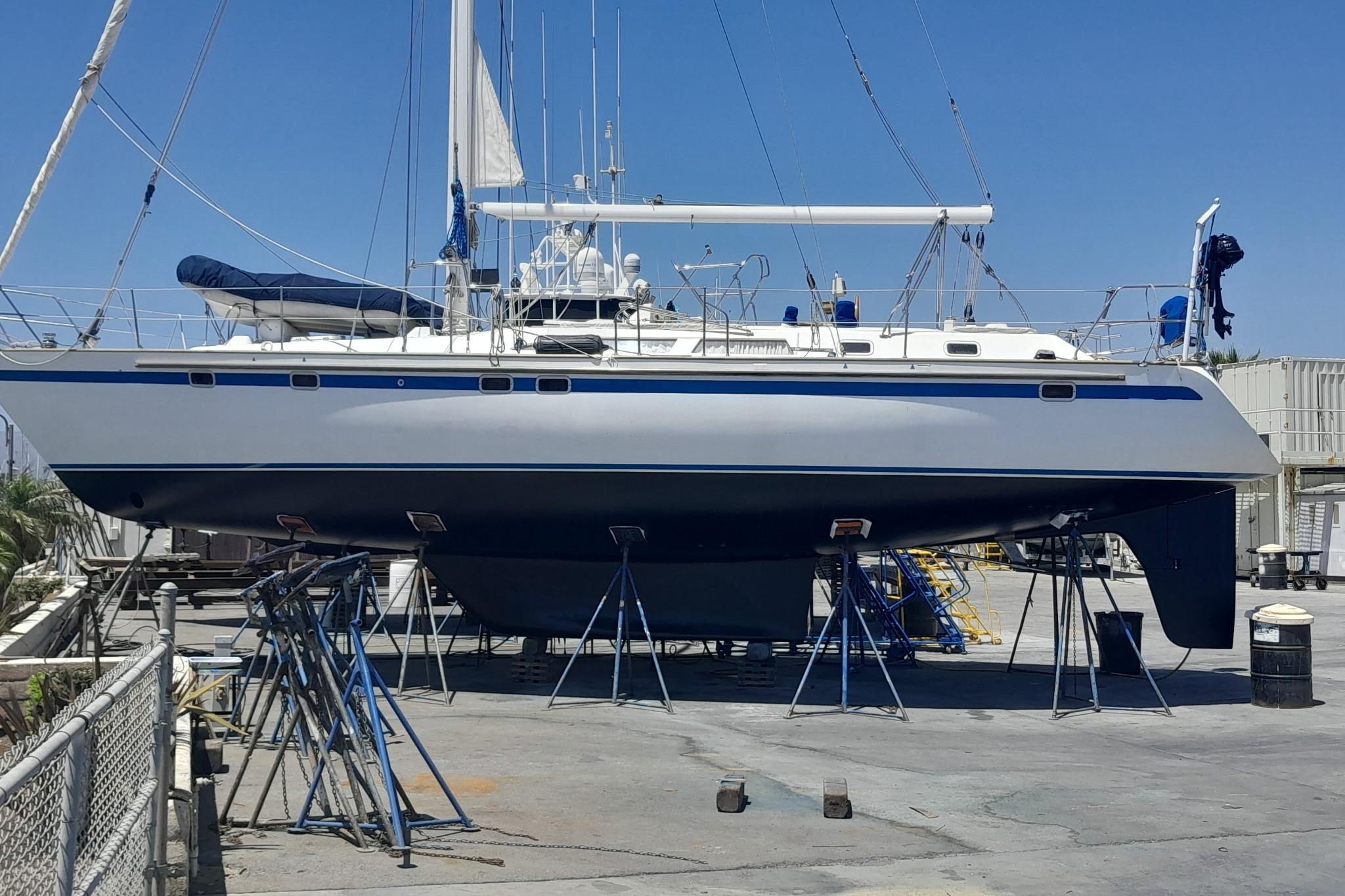 1991 Taswell Sloop sailboat on stands in a shipyard under clear blue sky.