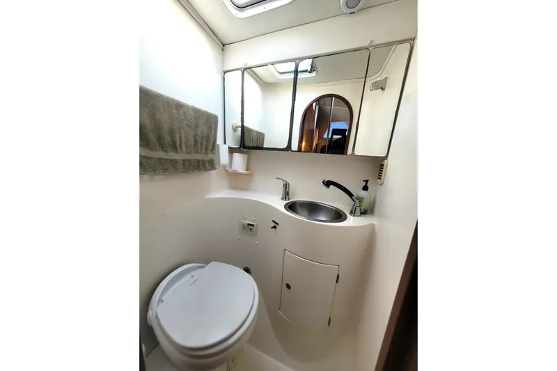 Ki Zen Yacht Photos Pics Compact bathroom in a 1995 Lagoon TPI boat with toilet, sink, and mirror.