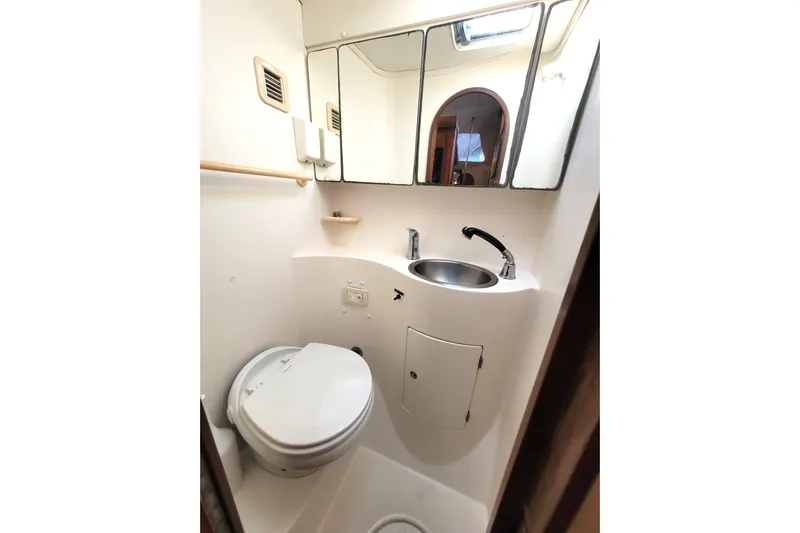 Ki Zen Yacht Photos Pics Compact bathroom in 1995 Lagoon TPI boat with toilet, sink, and mirror.
