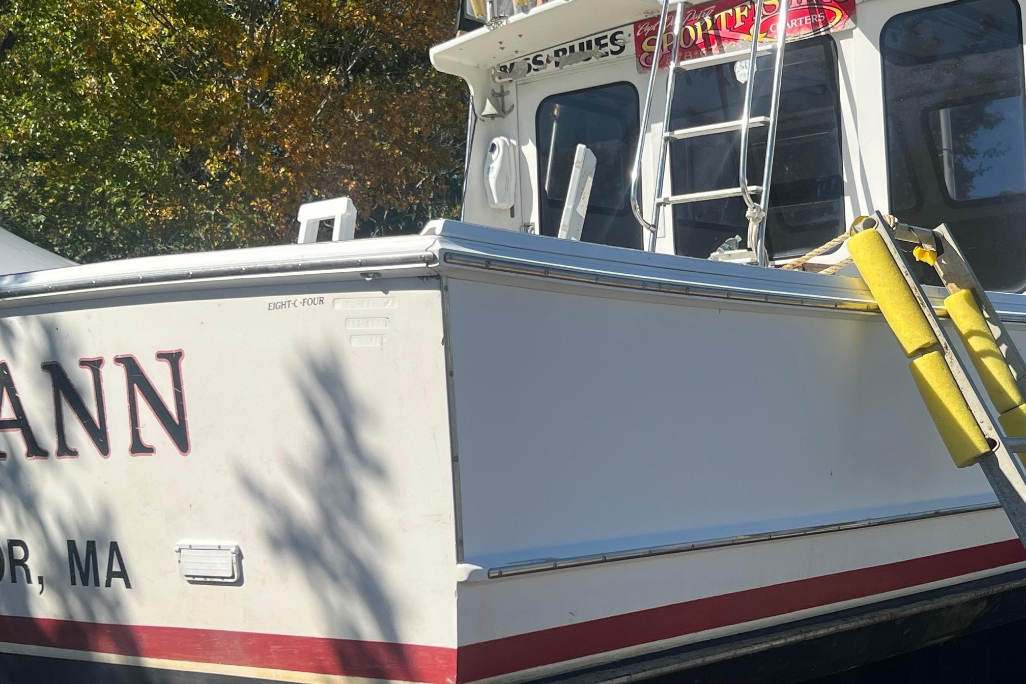 1995 Young Brothers 38 Fly Bridge boat with ladder and signage, docked outdoors.