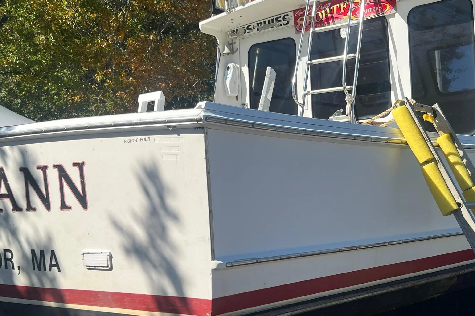 1995 Young Brothers 38 Fly Bridge boat with ladder and signage, docked outdoors.
