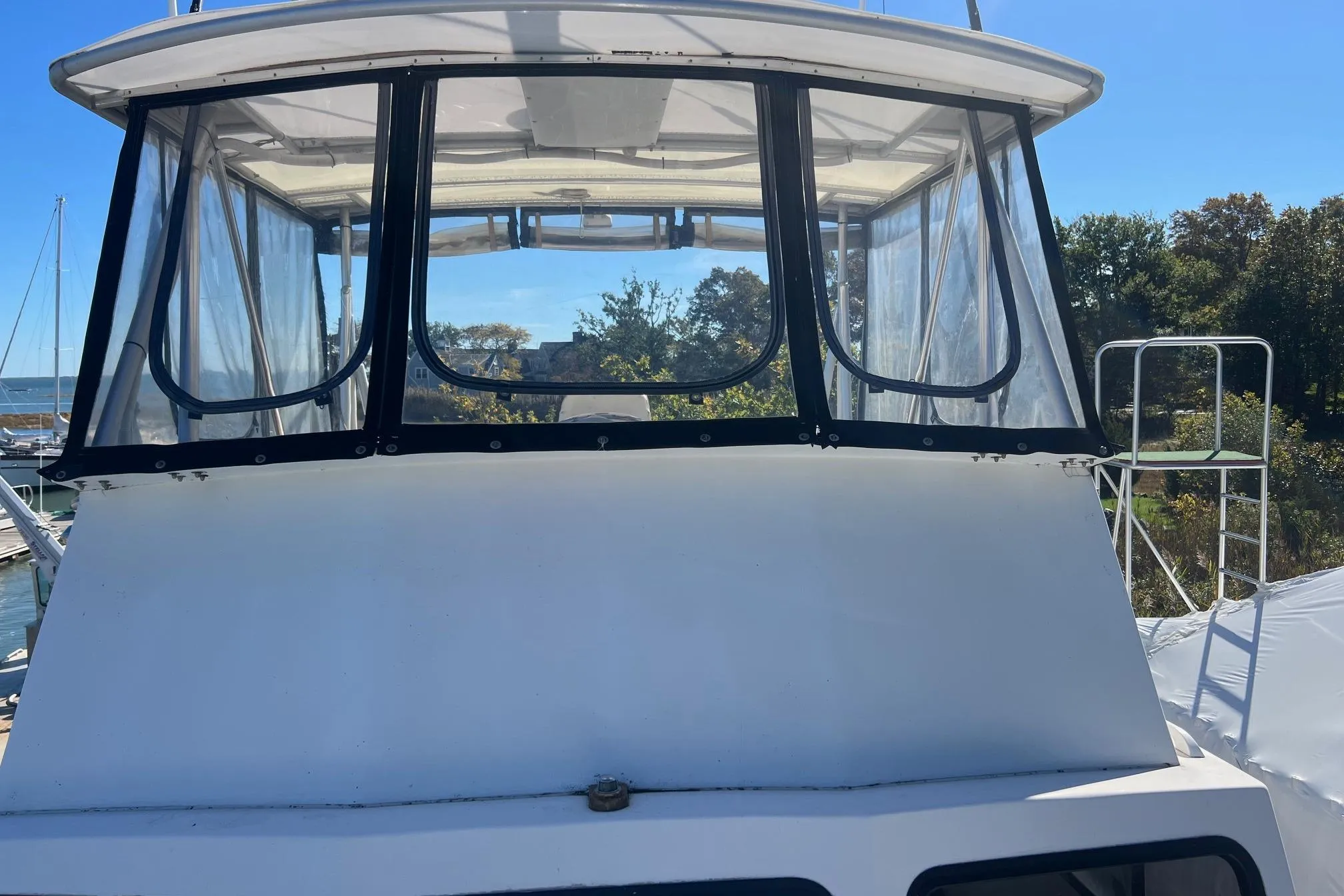 1995 Young Brothers 38 Fly Bridge boat with clear enclosure, docked in a marina.
