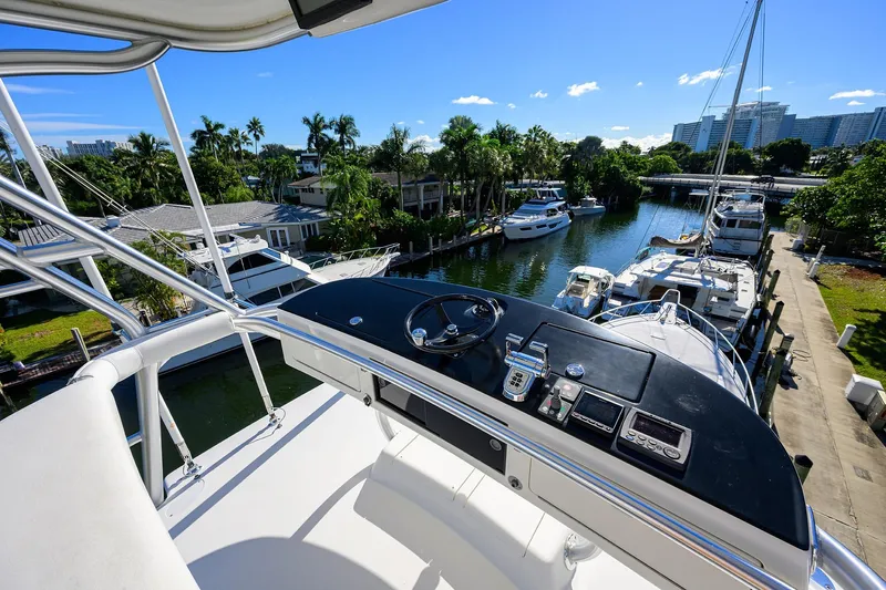 Osh-it Yacht Photos Pics 2014 Viking 76 Enclosed Bridge Convertible yacht overlooking marina with palm trees and clear sky.