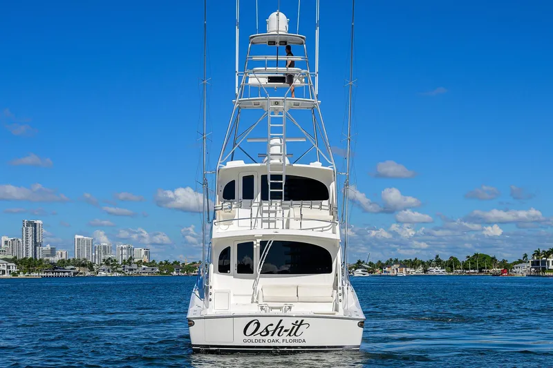 Osh-it Yacht Photos Pics 2014 Viking 76 Enclosed Bridge Convertible yacht on water, clear sky, cityscape background.