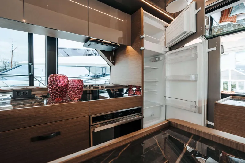  Yacht Photos Pics Modern kitchen interior of 2023 Prestige M48 Power Catamaran with open fridge and stylish decor.