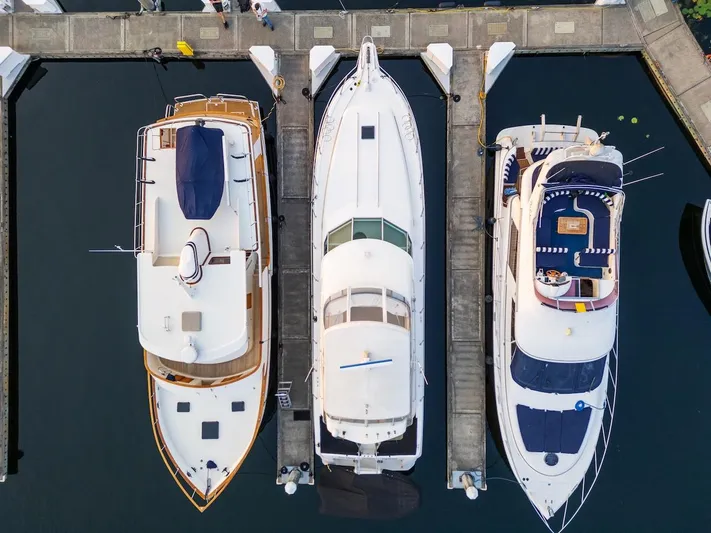 Too Many Options Yacht Photos Pics Aerial view of three yachts docked, featuring a 1993 Sea Ray 550 Sedan Bridge.